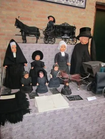 Poppen in zwarte en paarse rouwdracht bij een miniatuurkoets.
