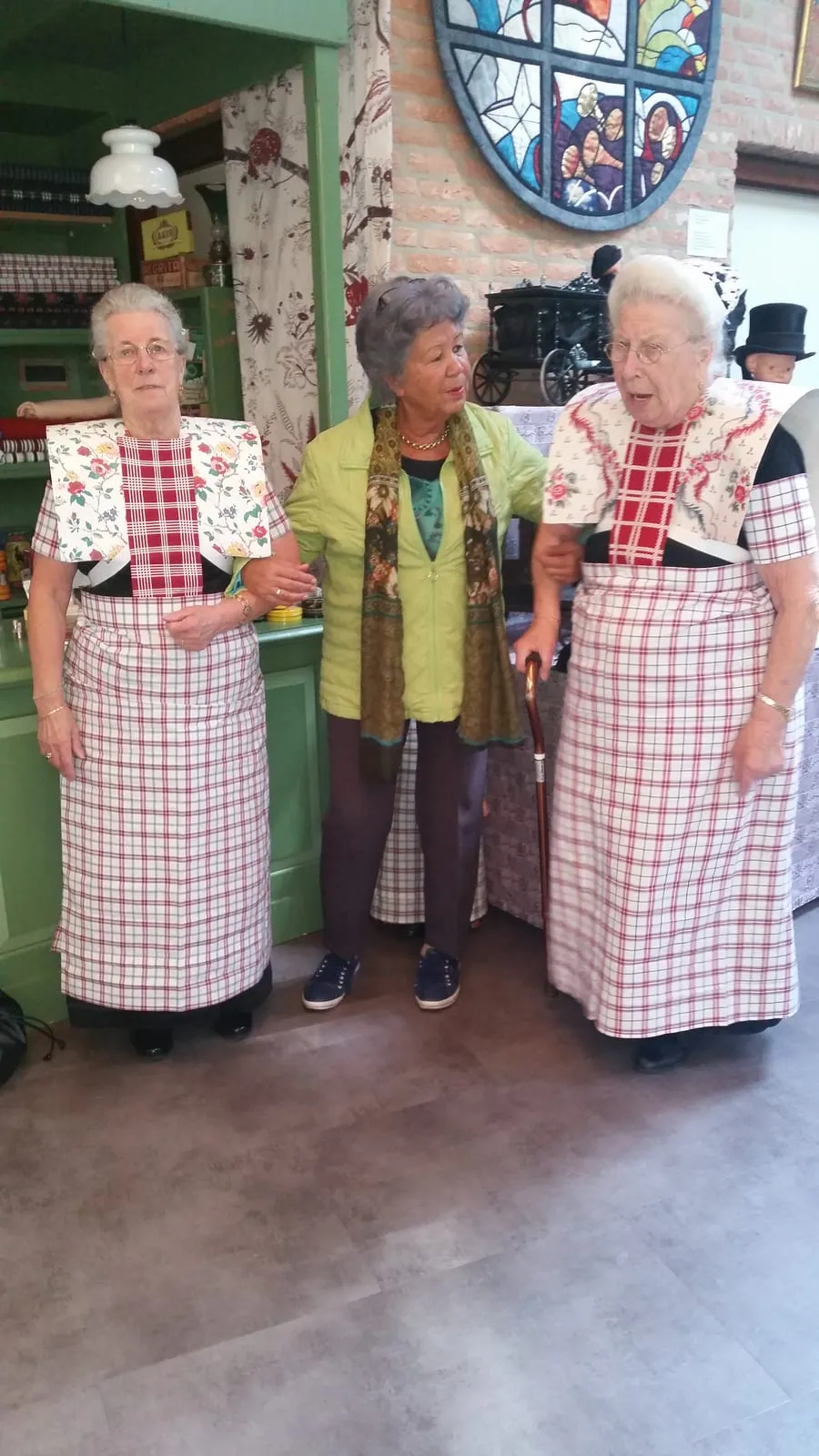 Drie vrouwen in Spakenburgse dracht poseren voor de foto in het museum.